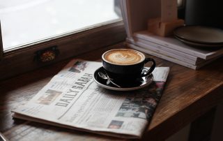 Black Ceramic Cup of Latte Art on Newspaper